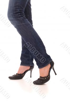 Woman legs dressed in jeans and black shoes walk forward