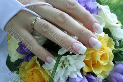 The gentle hand of the bride lays on a bouquet