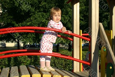 Toddler standing on playground in sunset lights