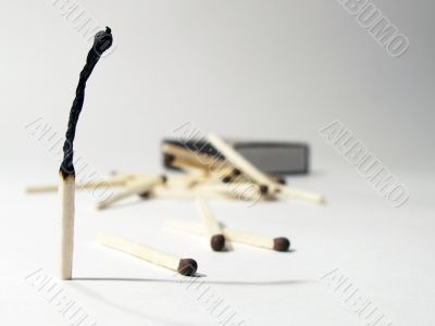 Burnt match standing on background with match-box