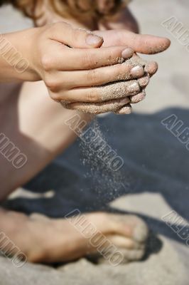 sand dropping down through girl`s fingers