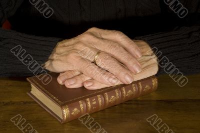 Old hands resting at antique bible