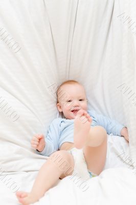 Little joyful baby fall on white bed