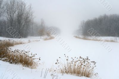 Lake in misty haze of winter blizzard