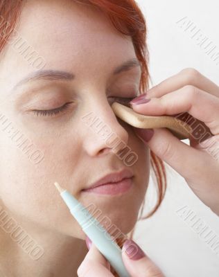 beautician is doing make-up to red-haired woman