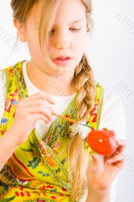 Young girl painting an easter egg red