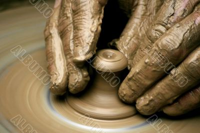 Hands of the potter on potter`s wheel