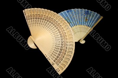 two hand-held fans on black background