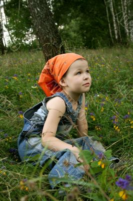 little girl sit on grass in forest