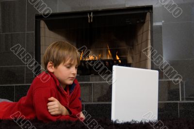 Boy at Fireplace on Computer. Boy at Fireplace on Computer.