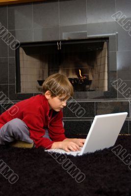 Boy at Fireplace on Computer. Boy at Fireplace on Computer.