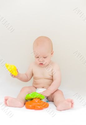 Little baby playing with toys over light gray background