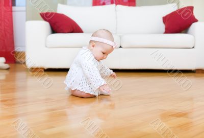 Happy baby girl tuching a hardwood floor