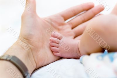 Man hold baby leg in hand