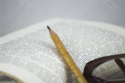 Pencil and glasses on a book