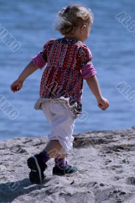 little girl at beach running through sand