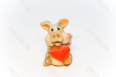 Stone figure of the pig holding red heart