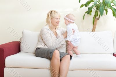 Mother and her baby girl seated on white sofa