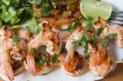 Grilled prawns on bamboo sticks served with salad and grilled ve