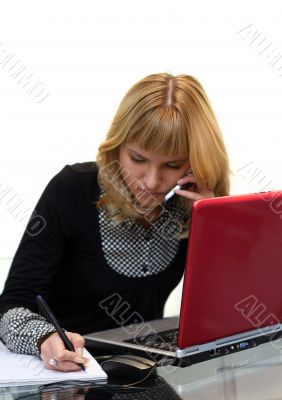 woman is writing and calling by phone sitting near laptop woman is writing and calling by phone sitting near laptop