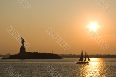 Statue of Liberty and sailing ship at sunset