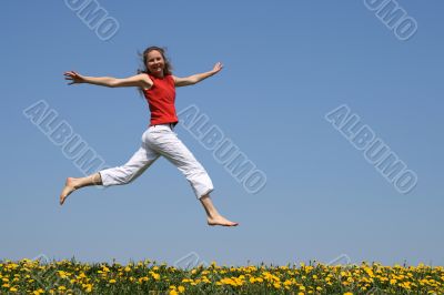 Girl flying in a jump over dandelion field