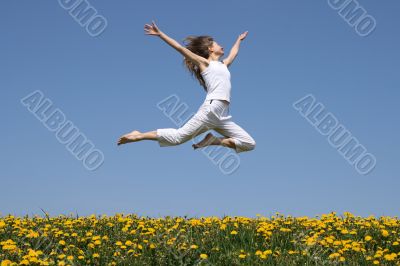 Girl flying in a jump over dandelion field