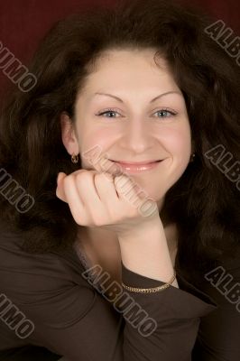 Portrait of the young smiling woman on a dark background.