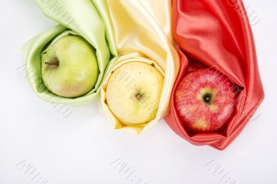 three apples of different colour wrapped in silk
