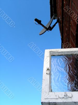Dish-shaped antenna and window against sky