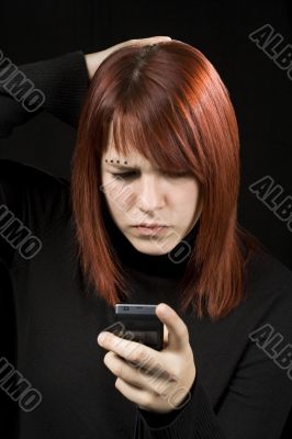 Girl scratching head while checking her mobile phone