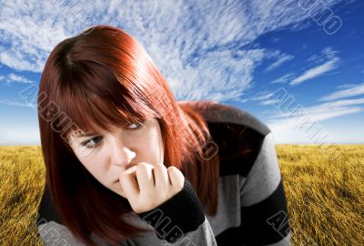 Pensive redhead girl biting nail