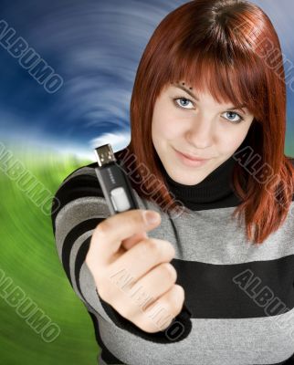 Redhead girl holding a flash drive at camera