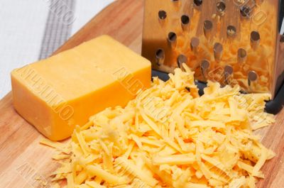 Grated cheddar cheese on wooden board