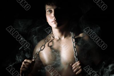 Muscular man with chain and smoke