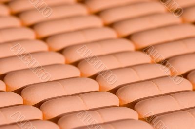 Rows of pink pills over white