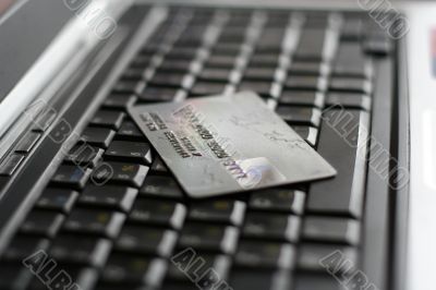 A shot of a laptop and a credit card in an office environment, can be used as e-commerce concept A shot of a laptop and a credit card in an office environment, can be used as e-commerce concept