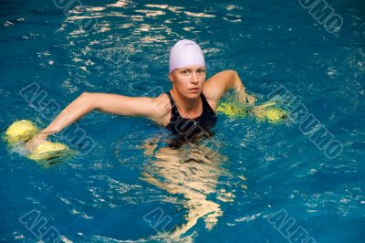 women in water with dumbbels looks in camera
