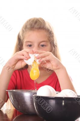 little girl cracking an egg over bowl