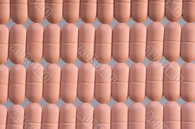 Rows of pink pills over grey