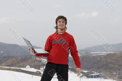 Happy teens with laptop in winter mountains