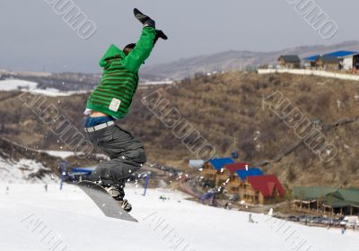 Snowboarder jumping at contest in mountains