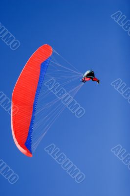 a paraplane flying high up in the deep blue sky