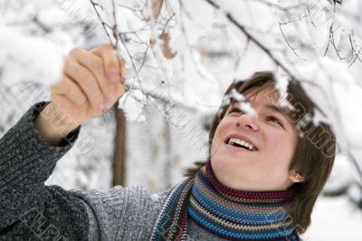 Teens boy with snown branch in winter
