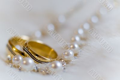 Two rings and pearl necklace lying on a white fur