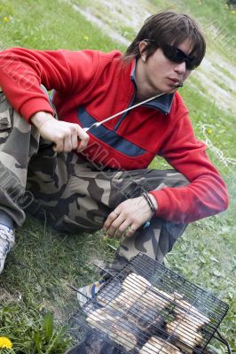 Teenager with barbecue outdoors in summer