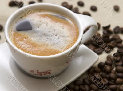 Cup of coffee and grains over sackcloth Cup of coffee and grains over sackcloth
