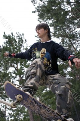 Teenager in Camouflage jumping by Skateboard