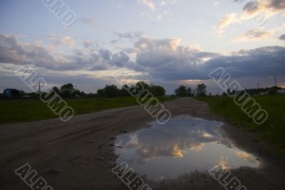 Clearing sky reflected in a puddle