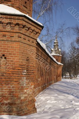 Old tall red brick wall of with decorated towers